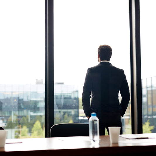 CEO viendo por la ventana de su oficina hacia el horizonte