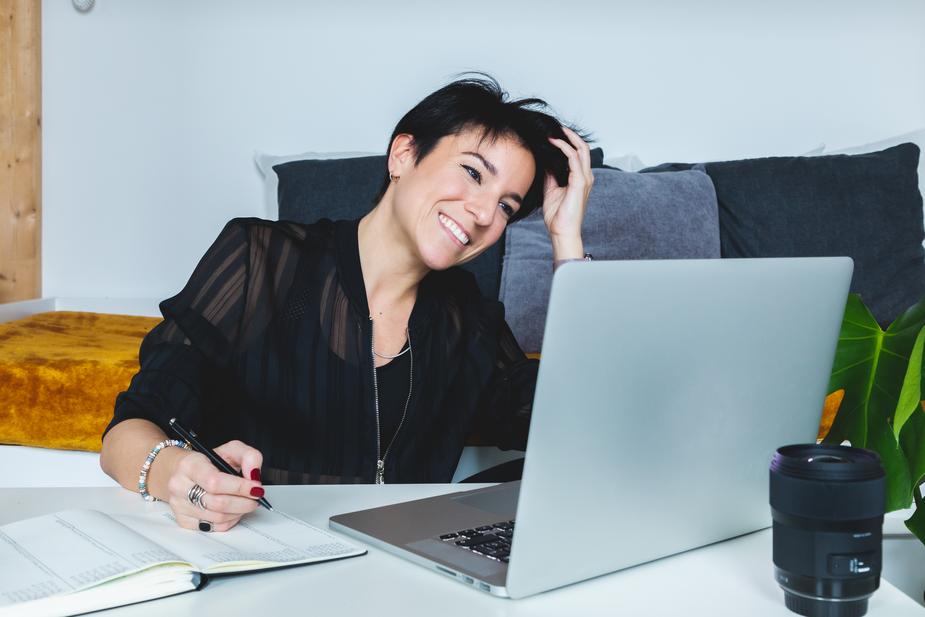mujer trabajando de home office mientras sonríe enfrente de su laptop